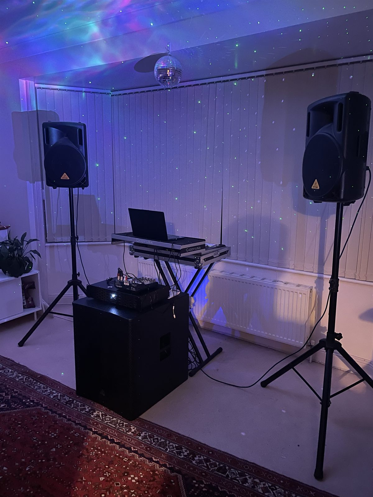The PA system viewed from the opposite side, with one speaker in the foreground and the DJ controller and laptop to the right.